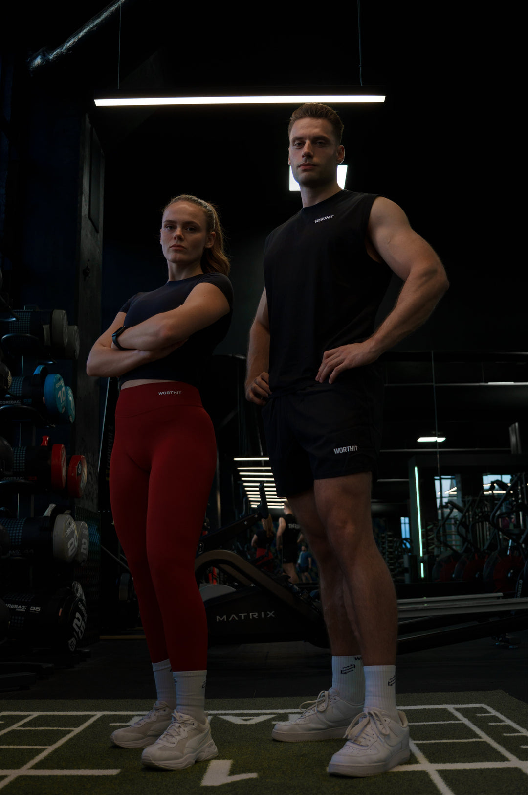 Two people standing in a gym setting with equipment in the background